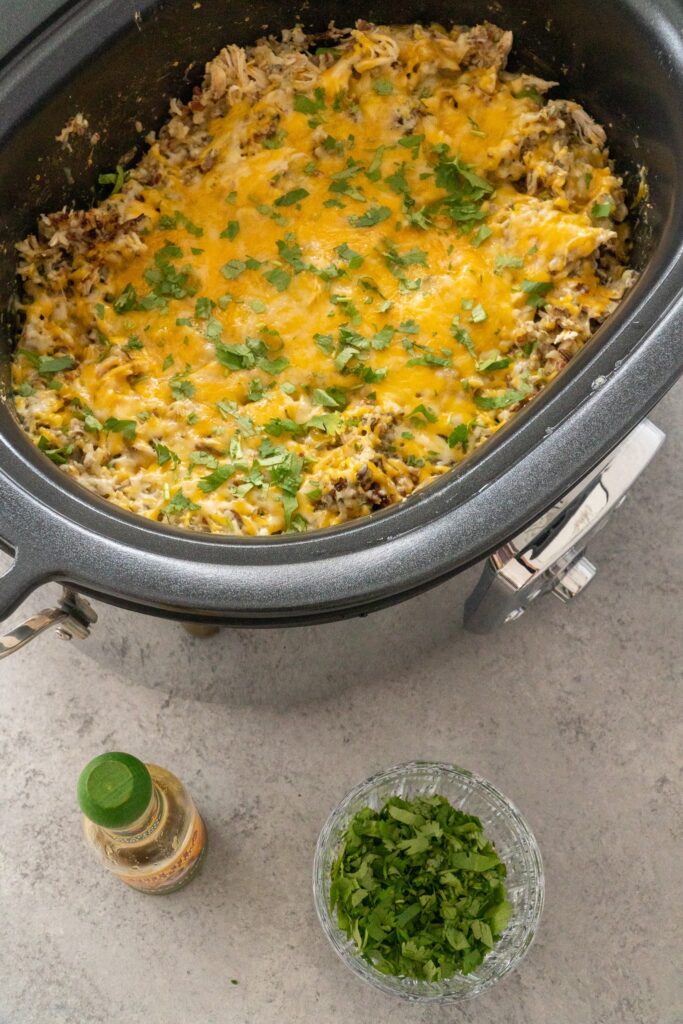 Salsa verde chicken and rice in crockpot with cilantro and hot sauce